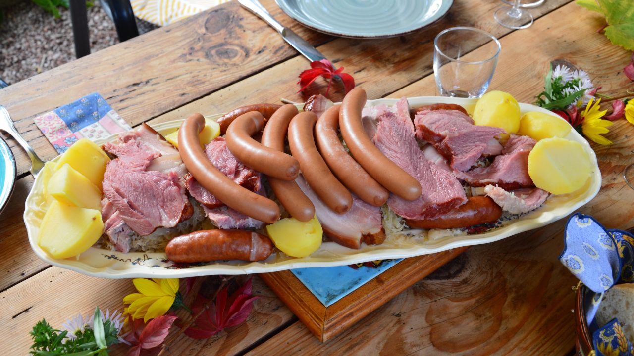 A beautifully arranged platter featuring sausages, meats, and potatoes on a rustic wooden table.